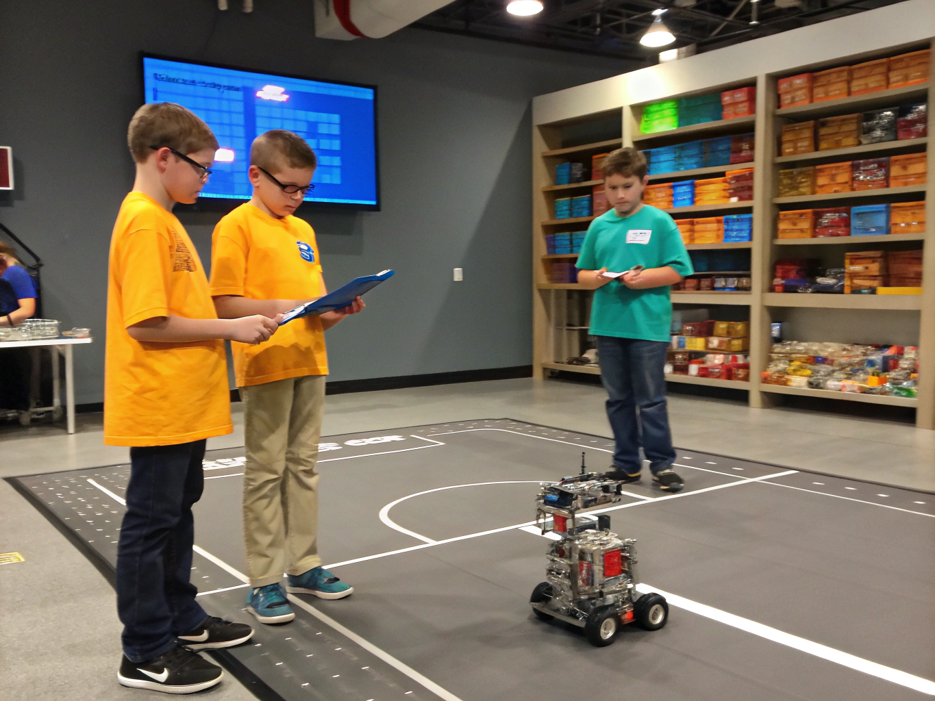 Huấn luyện viên cùng 4 học sinh Robotics phân tích chiến thuật trên sa bàn thi đấu tiêu chuẩn